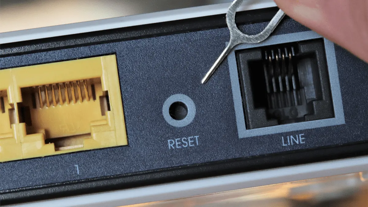 Eine Person drückt den Reset-Knopf eines Gerätes