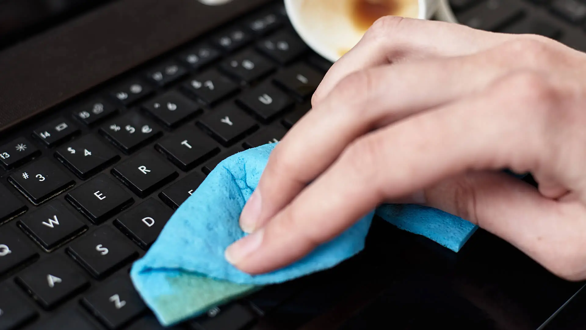 Hand reinigt Tastatur mit einem Lappen