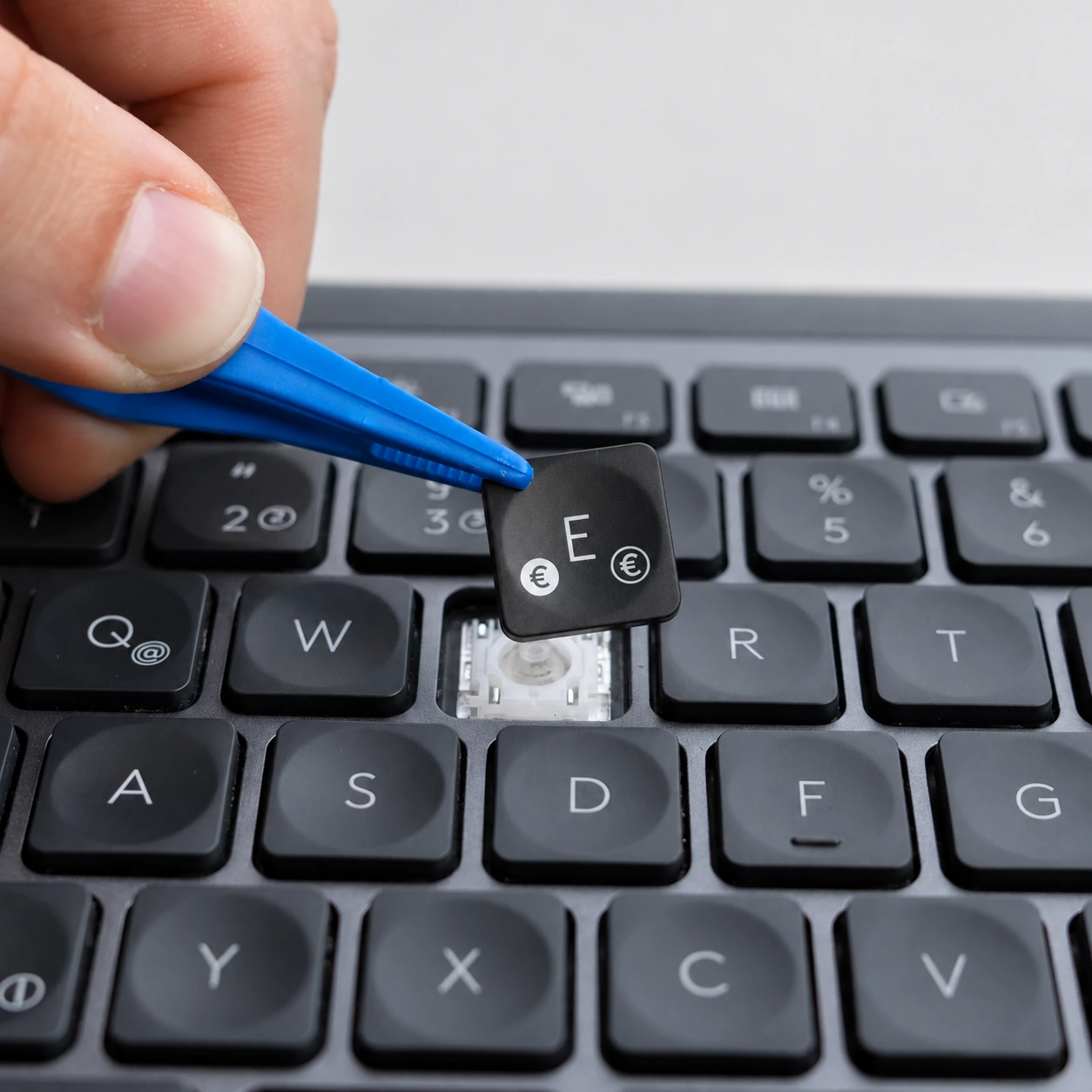 Eine Ersatztaste wird mit einem Werkzeug in eine Tastatur eingesetzt